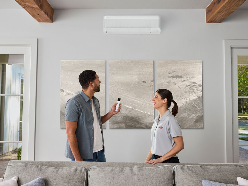 Man and woman looking at mini-split system on wall